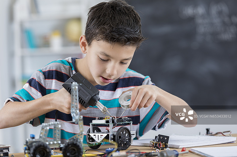 男学生在学校里专心组装机器人图片素材