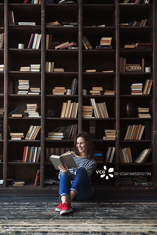 快乐的年轻女人在图书馆阅读图片素材