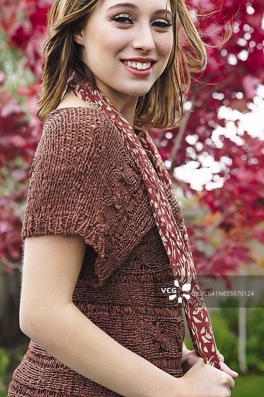 穿着针织毛衣、拿着围巾的年轻女人的肖像图片素材