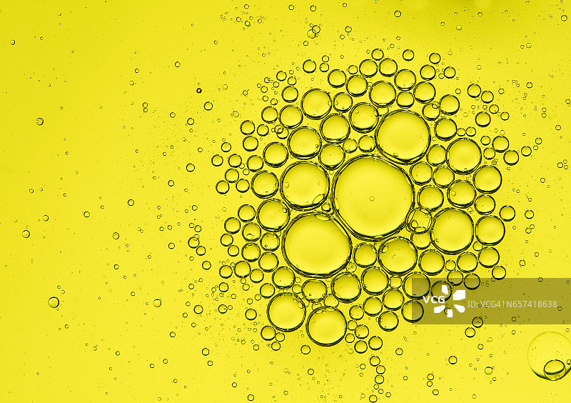 黄色背景上油滴气泡形成的圆形纹理图片素材