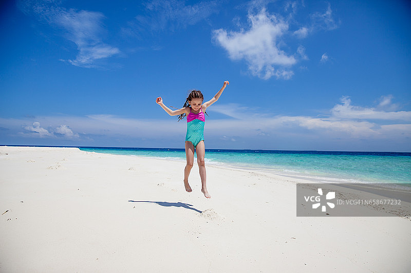 在热带海滩上玩影子的女孩图片素材