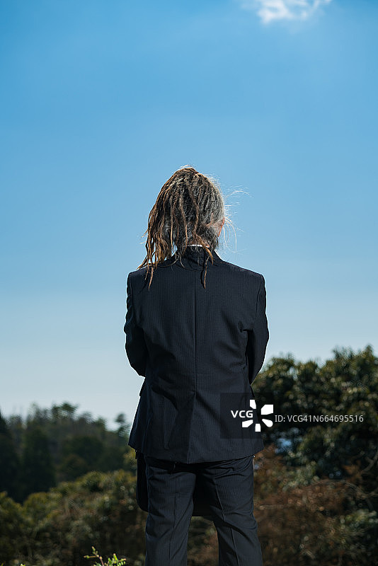 后视图的年长日本男子与雷鬼头穿西装在农村设置图片素材