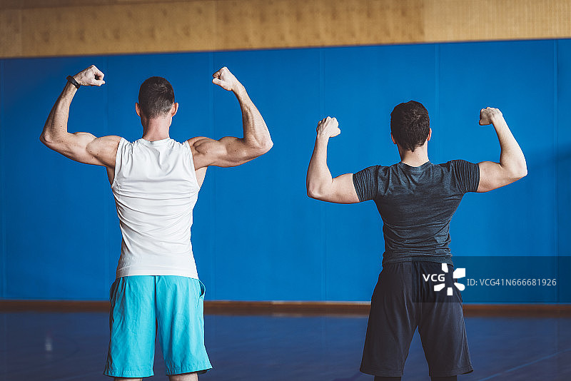 两位从背后展示肱二头肌的健壮男子图片素材