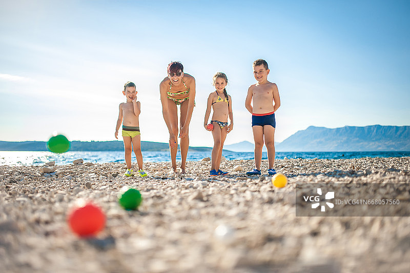 母亲与孩子沙滩玩滚球图片素材