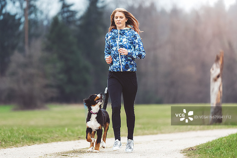 年轻女子与狗一起慢跑图片素材