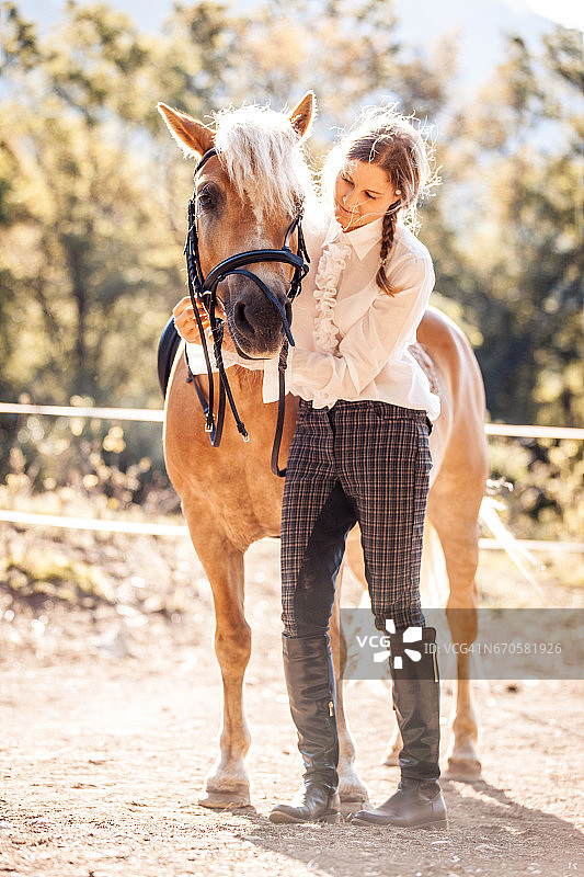年轻女子给她的马戴上笼头图片素材