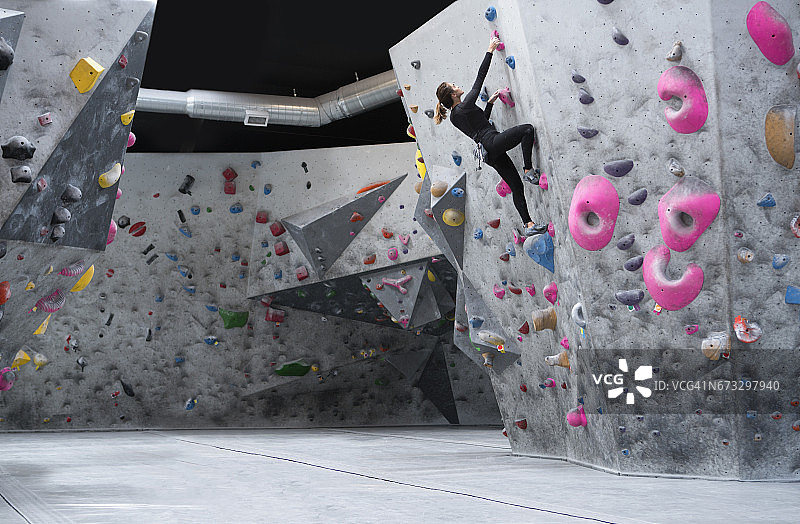 年轻女子攀登攀岩墙图片素材