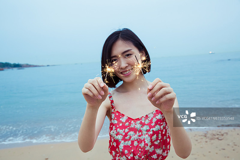 美丽女人在海滩上玩烟花棒图片素材