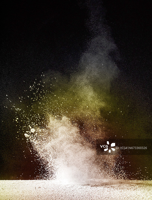 白色和黄色颗粒粉末云在黑色背景上爆炸图片素材