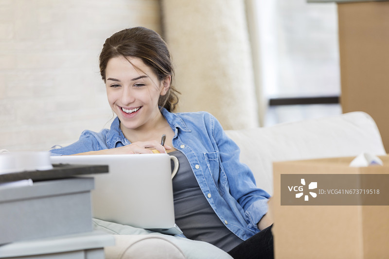 快乐的女人在新家中使用笔记本电脑图片素材
