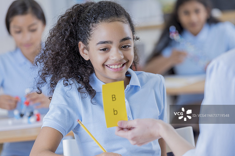 微笑的青少年学生在课堂上使用抽认卡图片素材