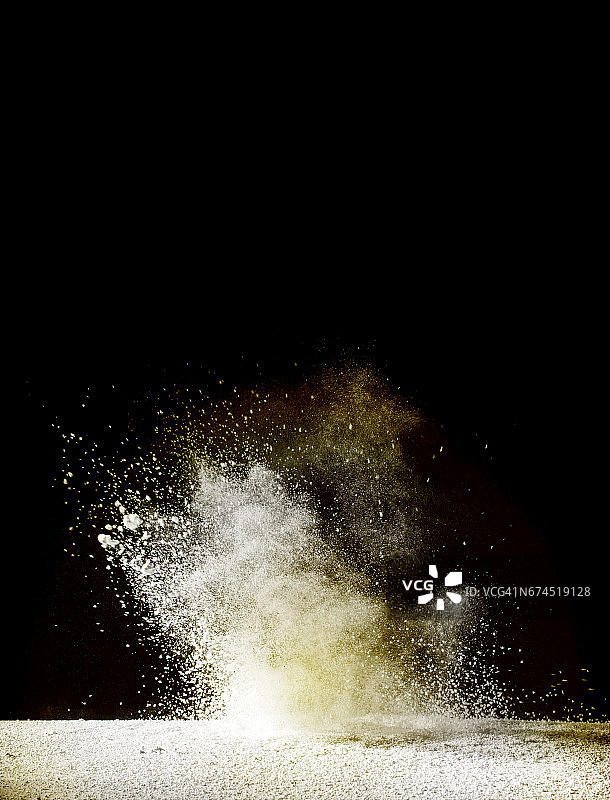 白色和黄色颗粒粉末云在黑色背景上爆炸图片素材