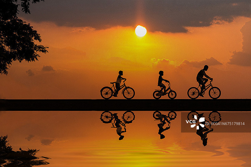 泰国日落时骑自行车的儿童剪影图片素材