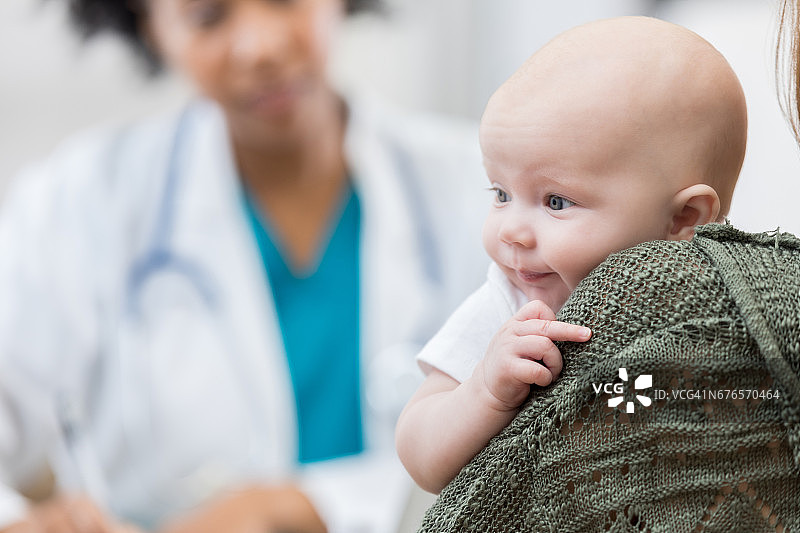 一位身份不明的母亲抱着心满意足的婴儿图片素材