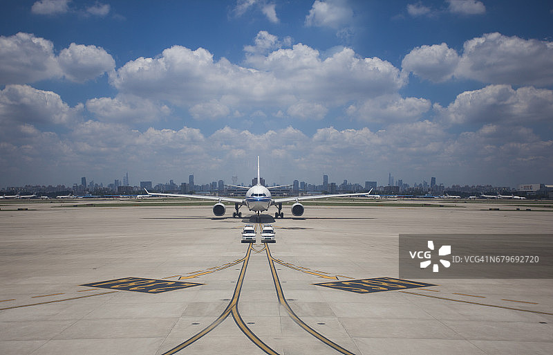 客机降落在机场后滑行至停车场，以上海城市景观为背景图片素材