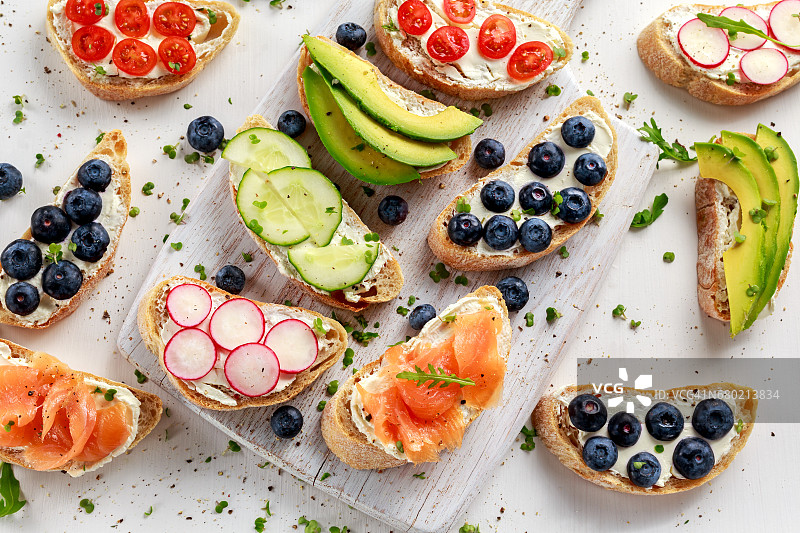 自制夏日吐司配奶油奶酪烟熏三文鱼、蓝莓、萝卜、黄瓜、牛油果和水芹沙拉，新鲜健康食品理念图片素材