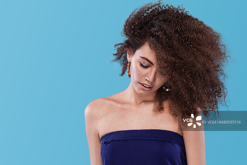 非裔发型女孩的美丽肖像，在蓝色背景上摆姿势，工作室拍摄，留白图片素材