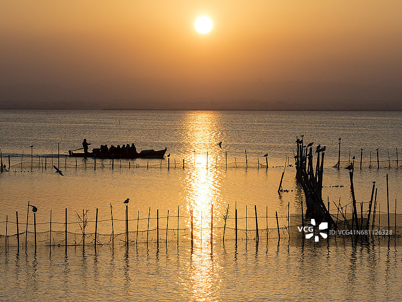西班牙瓦伦西亚阿尔布费拉湖日落，有木船和捕鱼陷阱图片素材