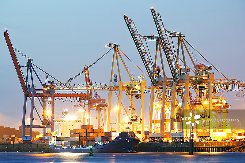 黄昏时分在德国汉堡港卸货的集装箱船图片素材