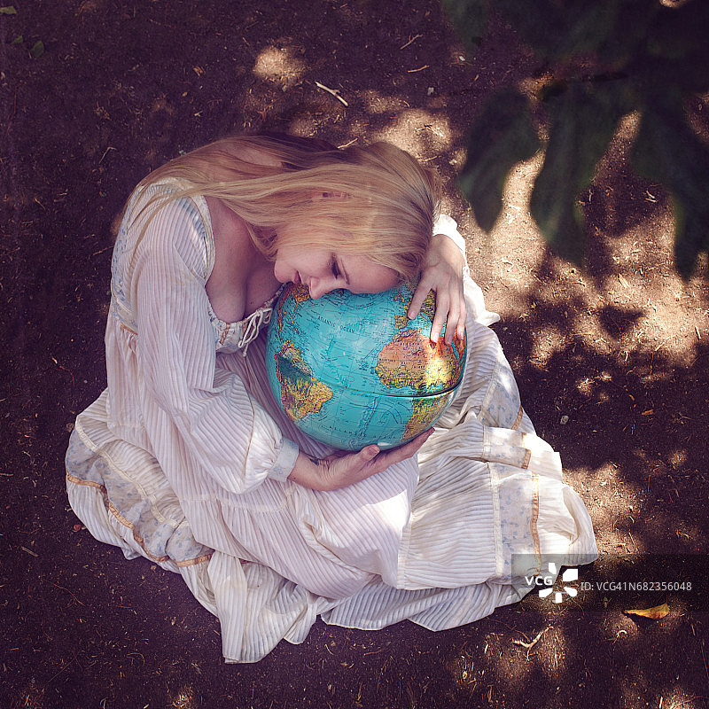 年轻女人坐着，怀抱着地球图片素材