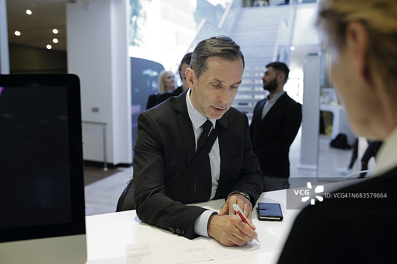 商人在前台办理酒店入住图片素材