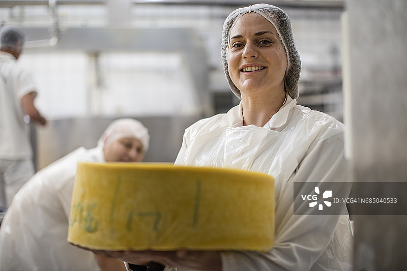 奶酪厂工人拿着贴有标签的奶酪轮图片素材