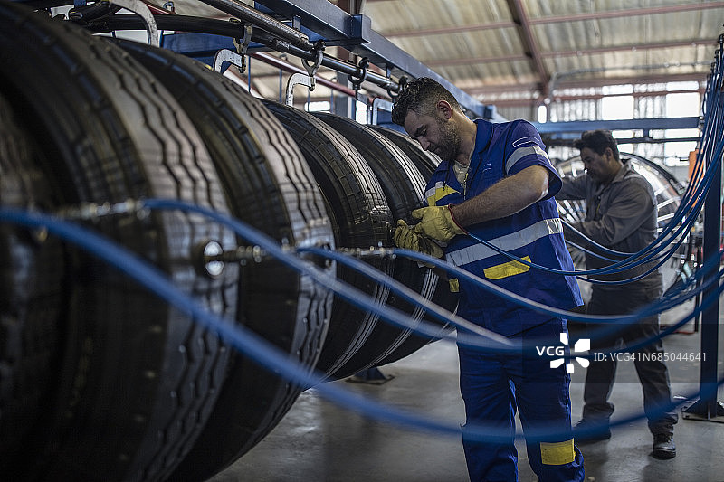 两名轮胎修理工正在给轮胎气门充气图片素材