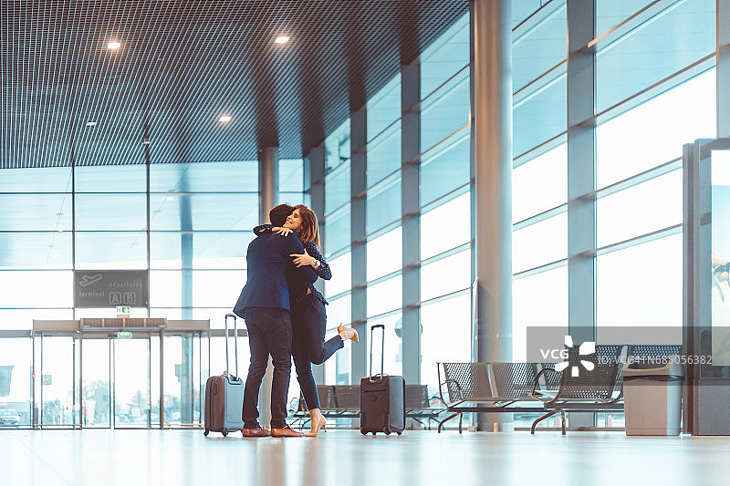 在机场航站楼拥抱年轻女人的商人图片素材