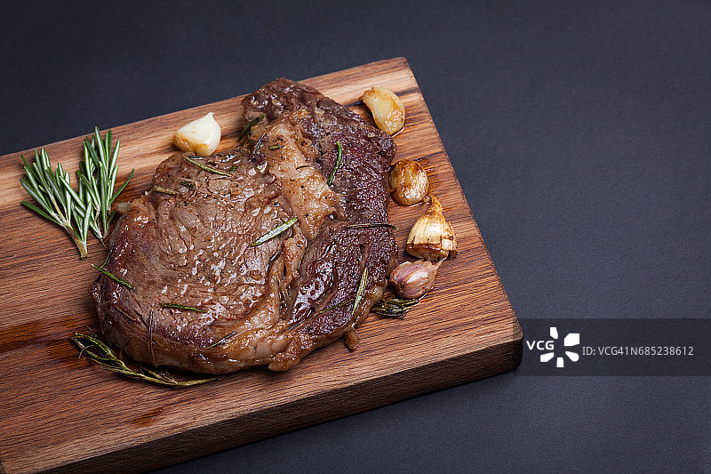 烤大理石纹肉眼牛排配香料，木板盛装，留白图片素材