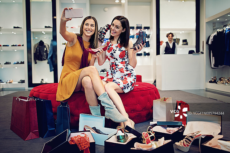 购物女孩们正在选择鞋子并与它们自拍图片素材
