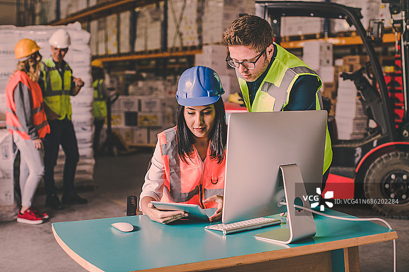 在仓库中使用平板电脑工作的商务同事图片素材