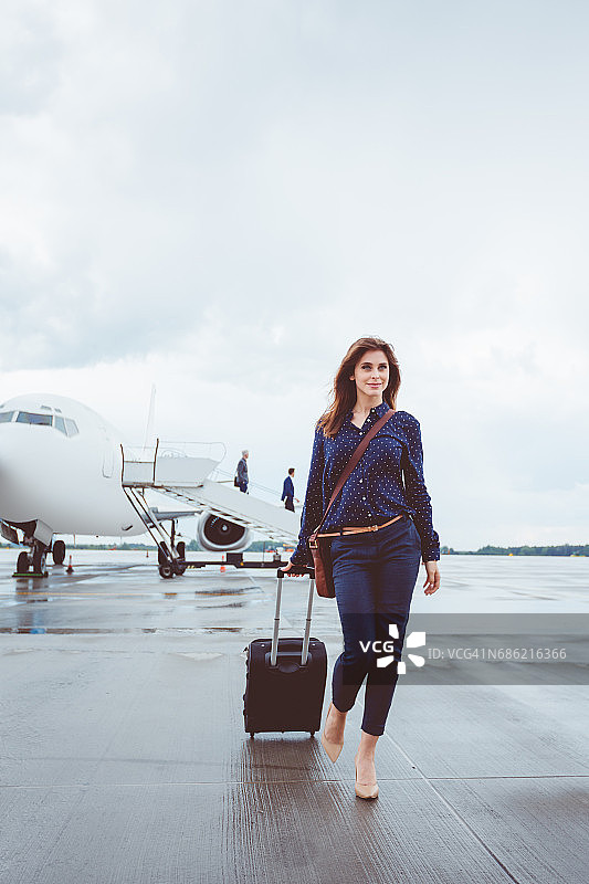 年轻漂亮的女商人走在飞机前图片素材