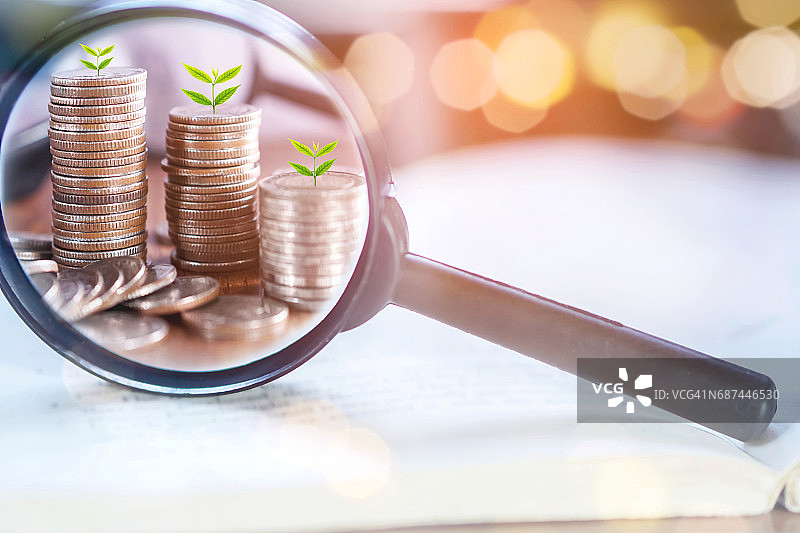 双重曝光商业概念：放大镜聚焦于硬币上生长的树木图片素材