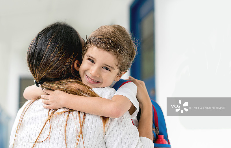 学校里快乐的男孩拥抱他的老师的肖像图片素材