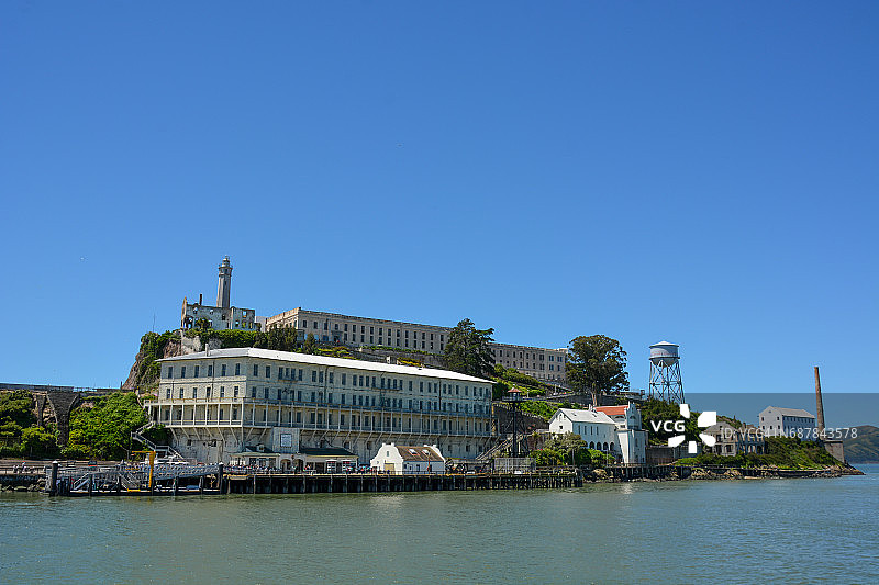 阿尔卡特拉斯岛，展示了码头设施、旧军事仓库、监狱和山顶上的灯塔图片素材