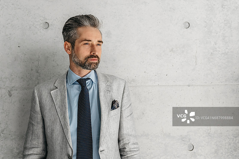 站在水泥墙前的英俊的络腮胡商人图片素材