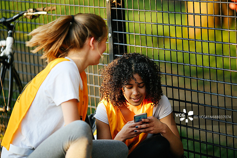 在室外篮球场看手机的青少年篮球运动员图片素材