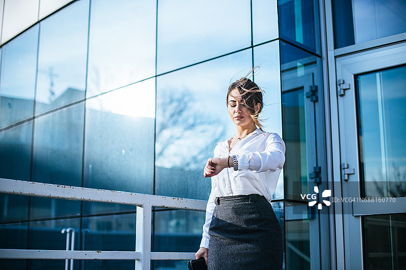 在办公室前查看时间的漂亮女商人图片素材