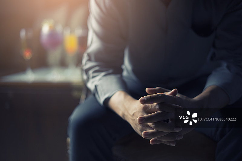 疲惫的商人手扶额头，面前放着鸡尾酒图片素材