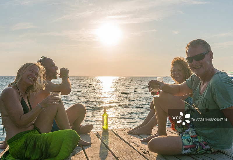 中年夫妇在日落时分的木制甲板上享用葡萄酒图片素材