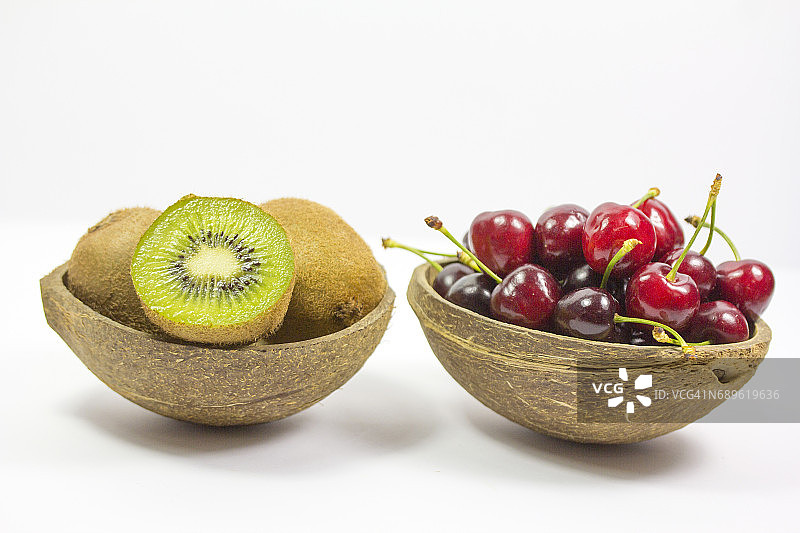 装满樱桃和猕猴桃的两个椰子壳图片素材