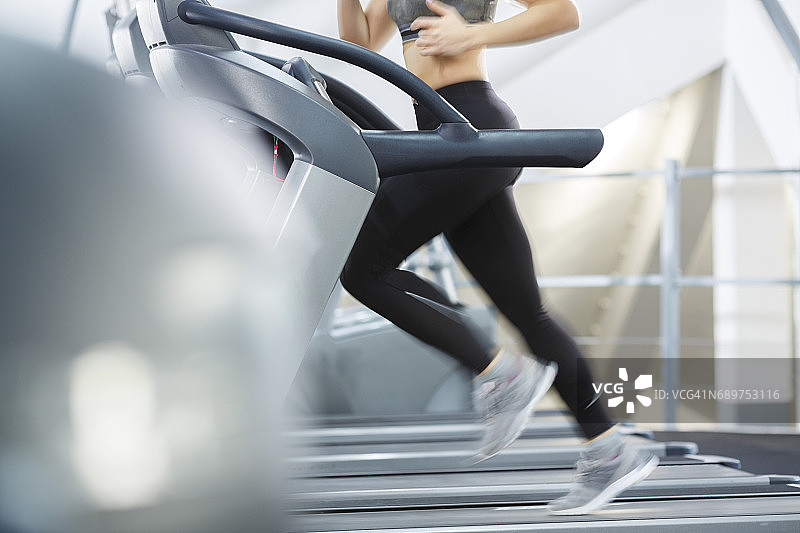 跑步机锻炼背景：特写镜头，运动中的双腿，健身房，在跑步机上跑步的健康女人，体育训练，运动女性图片素材