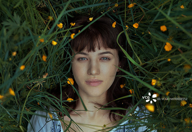 女人躺在绿草和黄色花朵中图片素材