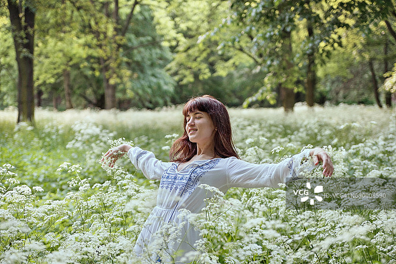 身穿白色连衣裙坠入白色花丛的女人图片素材