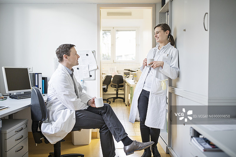 微笑的同事们在喝咖啡时交谈图片素材