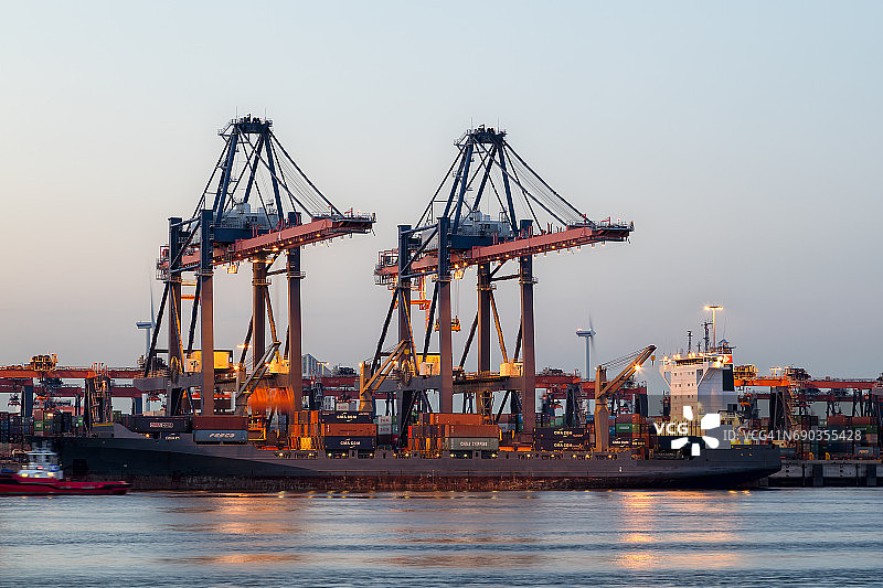 黄昏时分在德国汉堡港卸货的集装箱船图片素材