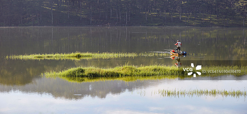 男子在湖中浮岛上钓鱼全景图图片素材