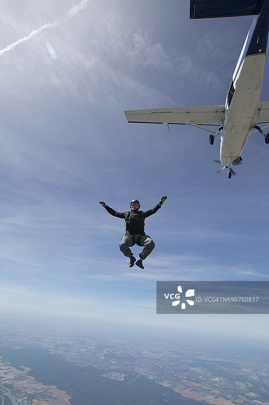 在飞机下方、湖泊上空自由落体的跳伞员图片素材
