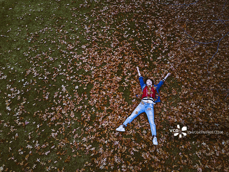 年轻女子躺在秋叶上的鸟瞰图图片素材