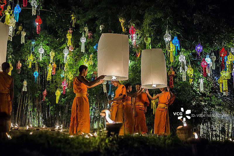 在泰国清迈点燃纸灯笼的年轻僧侣图片素材
